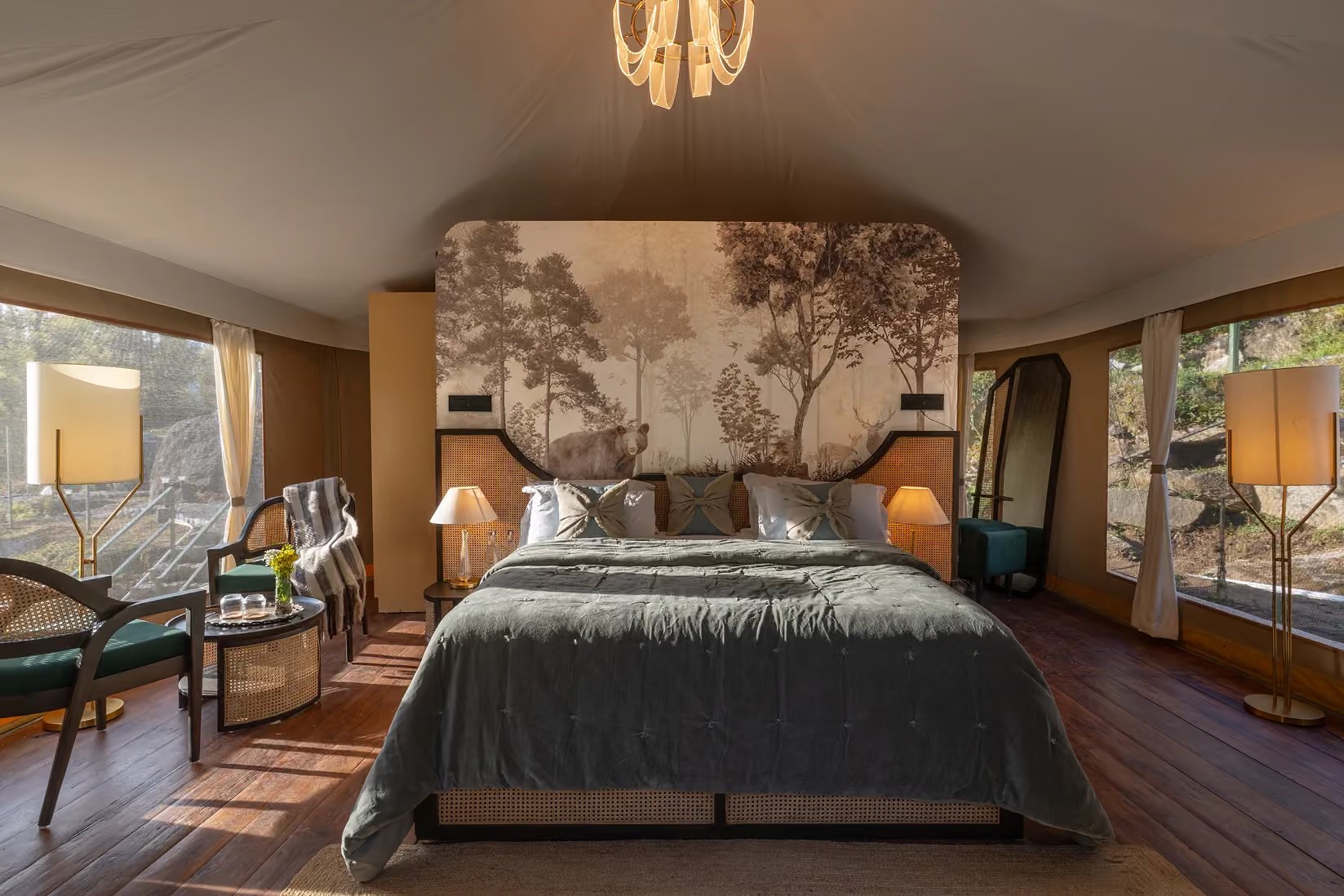 Tent bedroom with green bedding, woodland mural and seating at Saraaya Glamps near Dharamshala